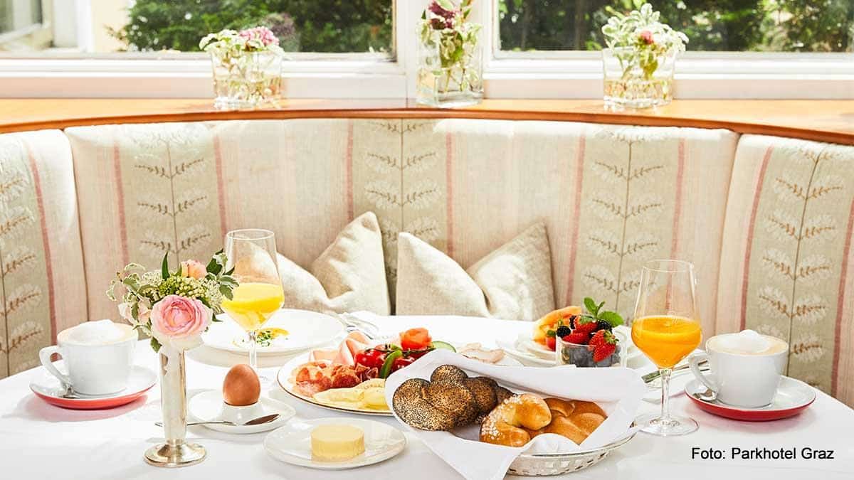Parkhotel Graz Gedeckter Frühstückstisch im Parkhotel Graz mit Gebäck, Ei, Orangensaft, Cappuccino, Wurst und Käseteller